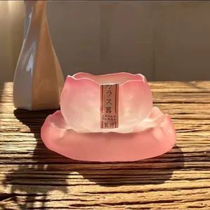 Close-up of pink frosted glass lotus-shaped teacup and saucer on wooden table