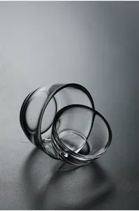 Close-up of two minimalist Japanese style clear glass tea cups on dark background