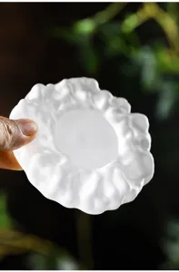 Primer plano de un posavasos de vidrio esmerilado blanco con bordes ondulados