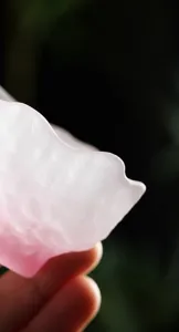 Detalle macro de una taza de té de vidrio rosa esmerilado con borde de pétalo irregular.