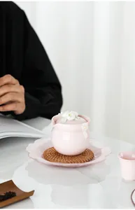 Detailansicht einer rosa Keramik-Teedose mit einem weißen Lotusblumen-Deckel