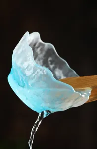 Primer plano de una taza de té de vidrio azul esmerilado con textura de hielo vertiendo agua.