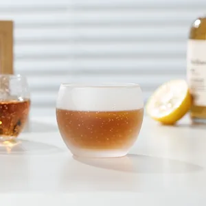 Hand-blown round bubble glass cup for whiskey and tea in a lifestyle setting.