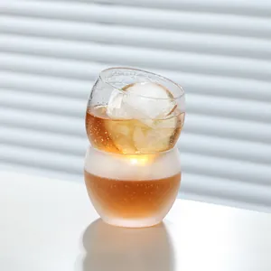 Premium hand-blown thick round whiskey glass cup with a large ice ball in bright natural light