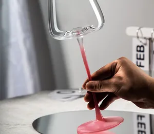Nahaufnahme eines eleganten Kristallweinglases mit rosa Stiel über einem Reflexionsspiegel