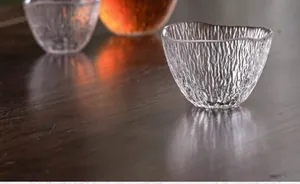 Exquisite japanische Teetasse aus strukturiertem Glas auf einem dunklen Holztisch