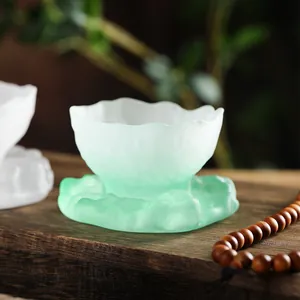 Frosted mint green glass teacup with saucer in elegant lotus leaf design.