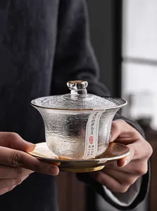 Detail einer Kristallglas-Gaiwan-Teeschale mit Goldrand und Hammerschlag-Textur in Händen