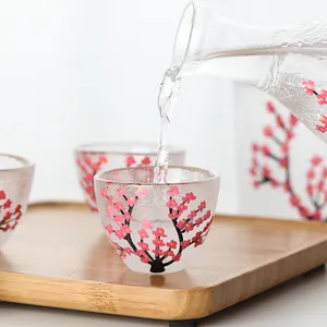 Elegantes Sake-Set aus Glas mit Kirschblütenmuster, Karaffe und Becher auf Holztablett