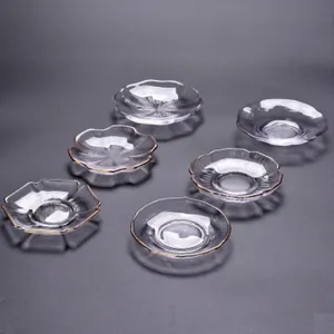 Set aus Glasuntersetzern mit Goldrand in verschiedenen Blumenformen auf dunklem Grund