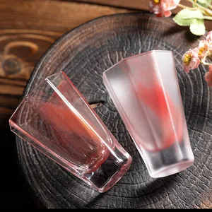 Heat-resistant octagonal glass tea cups with red artistic swirl patterns on wood