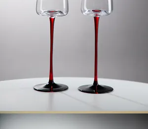 Dettaglio ravvicinato di calici in cristallo di lusso con eleganti steli rossi lunghi