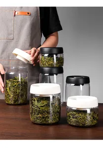 Vacuum sealed glass tea storage jars with black and white lids shown on wood table