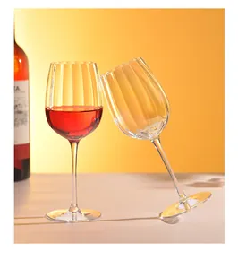 Close-up of elegant vertical striped crystal wine glasses against a warm sunset background.