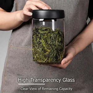 Clear glass vacuum sealed tea storage jar being held against an apron background.