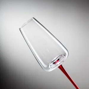 Elegante flûte da champagne in vetro trasparente con un sottile stelo rosso su fondo grigio