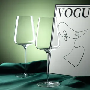 Elegantes Set aus Bordeaux-Kristallweingläsern auf grünem Stoff, minimalistisch.