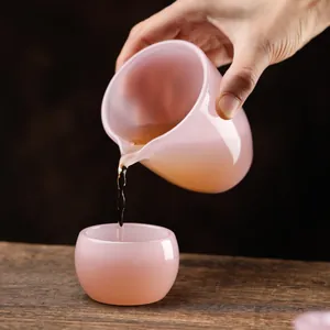 Elegant pink translucent glass tea set featuring a pitcher and cup on wooden surface
