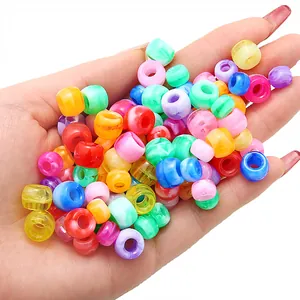 Hand-held assortment of colorful acrylic large hole barrel beads for DIY jewelry making