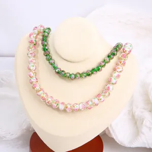 Detail view of faceted glass wheel beads with pink floral and green patterns for DIY