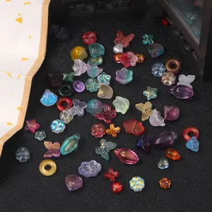 Detalle de cuentas de vidrio variadas con forma de mariposa y flor para crear joyas DIY.