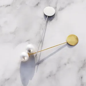 Detailansicht von Perlenbroschen-Nadeln in Gold und Silber auf einer Marmoroberfläche