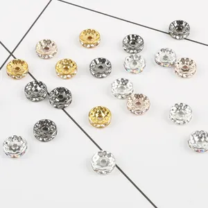 Dettaglio macro di varie perline distanziatrici con strass oro e argento per gioielli.