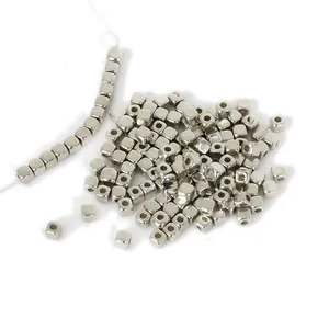 Primer plano de pequeñas cuentas espaciadoras de cubo CCB plateadas para joyería DIY.