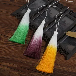 Three beautiful gradient tassels in green, purple, and yellow on a wooden background