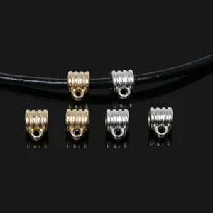 Macro detail of gold and silver textured pendant bails shown on a black cord