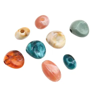 Nahaufnahme unregelmäßiger Acrylperlen mit Bernsteintextur und großen Löchern für DIY-Schmuck.