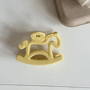 Detail view of a cute light yellow rocking horse shaped hair claw clip fashion accessory