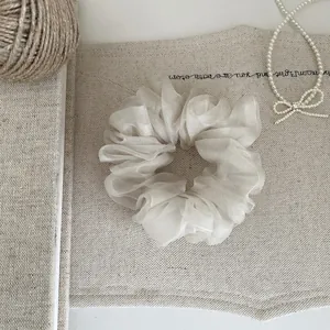 Detailaufnahme eines eleganten beige Organza-Netz-Haargummis mit luftigem Bubble-Design