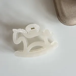 Close-up of a minimalist cream rocking horse hair claw clip with a pearlescent finish
