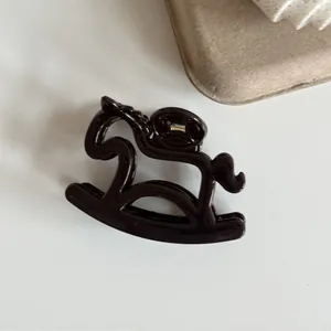 Detail view of a cute rocking horse hair claw clip in glossy brown finish.