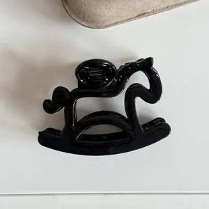 Detailed view of a cute black rocking horse shaped hair claw clip for women's hair style.
