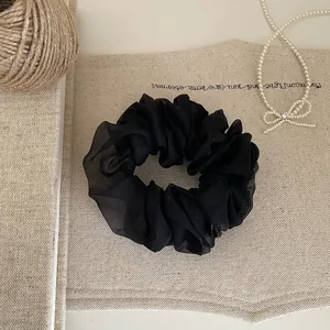 Detailansicht eines eleganten schwarzen Organza-Haargummis mit luftigem Netz-Look