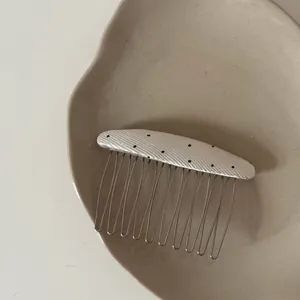 Close-up detail of a minimalist Korean-style oval hair comb with black polka dots