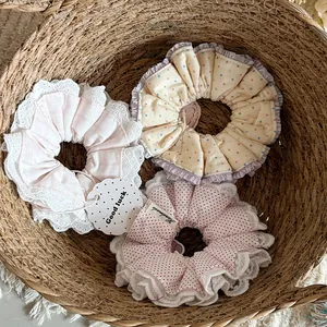 Detail view of three handmade cotton scrunchies with lace edges and polka dot patterns