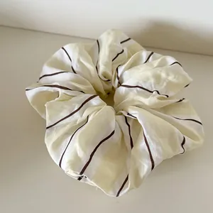Primer plano de coletero de tela a rayas amarillo crema y blanco para el pelo.