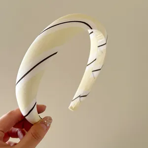 Primer plano detallado de una diadema ancha de tela a rayas amarillo crema y blanco
