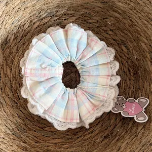 Close-up of handmade plaid cotton scrunchie with delicate white lace trim and cute heart tag.