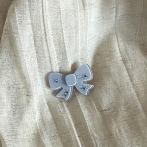 Detailed view of an ice-blue frosted bow hair clip with sparkling blue rhinestones.