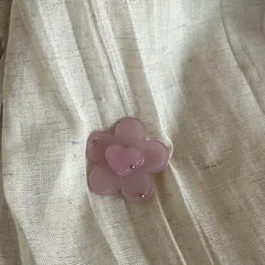 Close-up of a sweet pink translucent flower hair clip with a heart center and tiny rhinestones