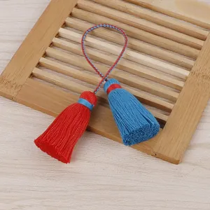 Gros plan détaillé de glands en coton rouge et bleu faits main sur un support en bambou