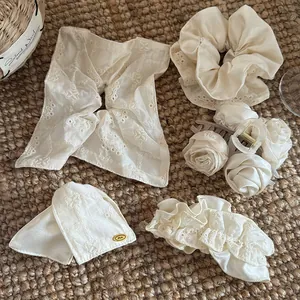 Detailweergave van beige kanten scrunchies, bloemen haarklemmen en strikspelden.