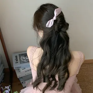 Detailed macro view of a sweet pink satin bow hair comb accessory on styled wavy hair