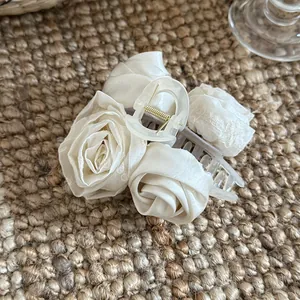 Detailopname van een crème satijnen rozen haarklem met verfijnde kanten rand