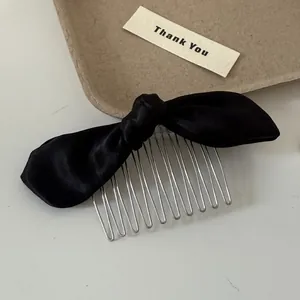 Detailed view of elegant black satin bow hair comb with durable silver metal teeth