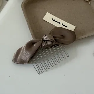 Macro detail of a coffee-colored satin bow hair comb with metallic teeth